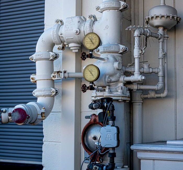 Close-up shot of an industrial pipe system featuring pressure gauges and valves outdoors.